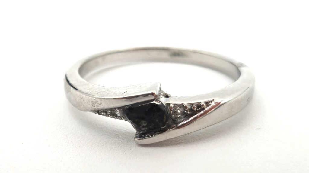 Bague argentée sertie d'un fragment de météorite noir, sur fond blanc