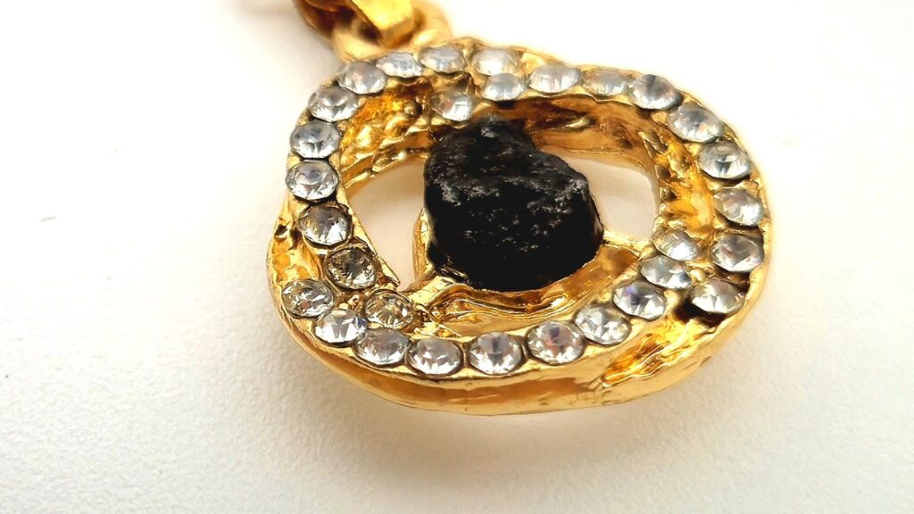 Pendentif doré serti de zircons autour d'un fragment de météorite noir