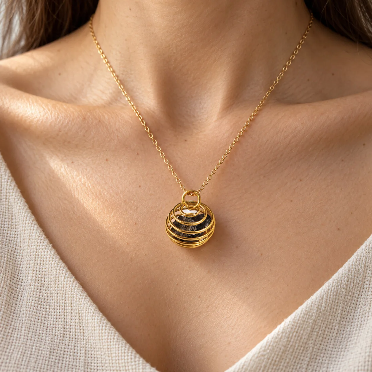 Pendentif cage spirale dorée – Campo del Cielo, sans chaîne – porté (mise en situation)